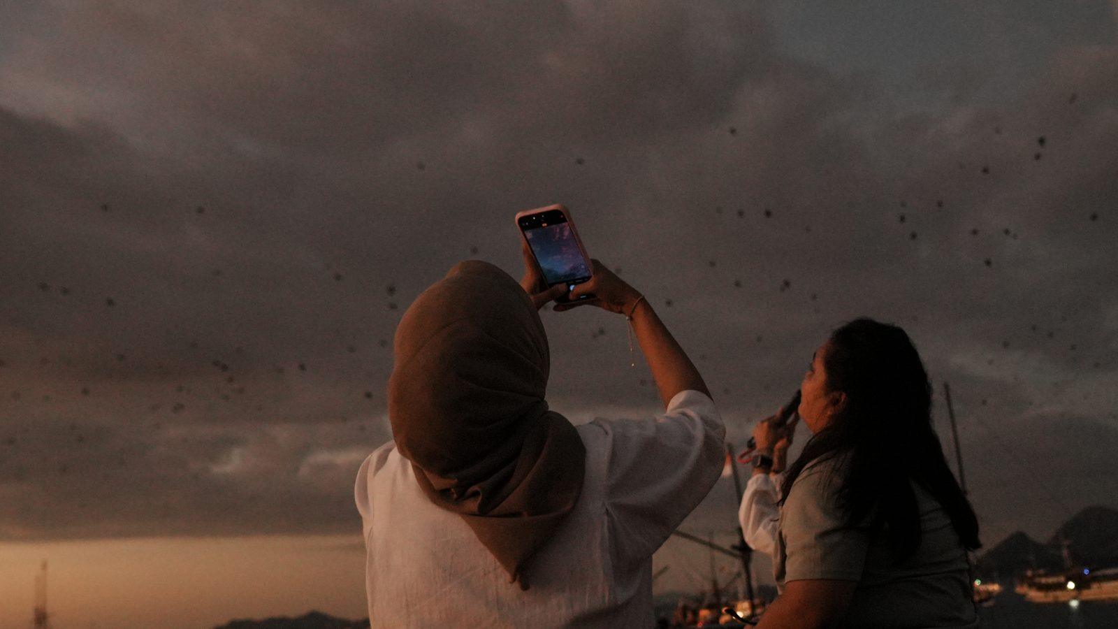 Kalong – Woman photographed as bats fly overhead (Foto real de un viaje de Komodo Explorer)