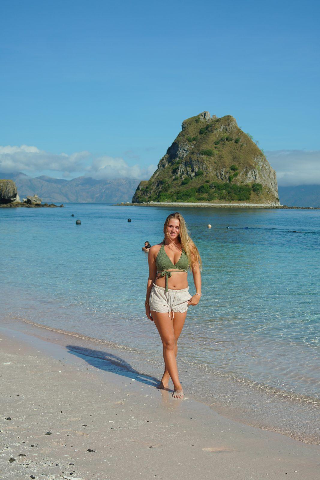 Kelor – woman standing on sand, islet behind (Echtes Foto von einer Komodo-Explorer-Fahrt)