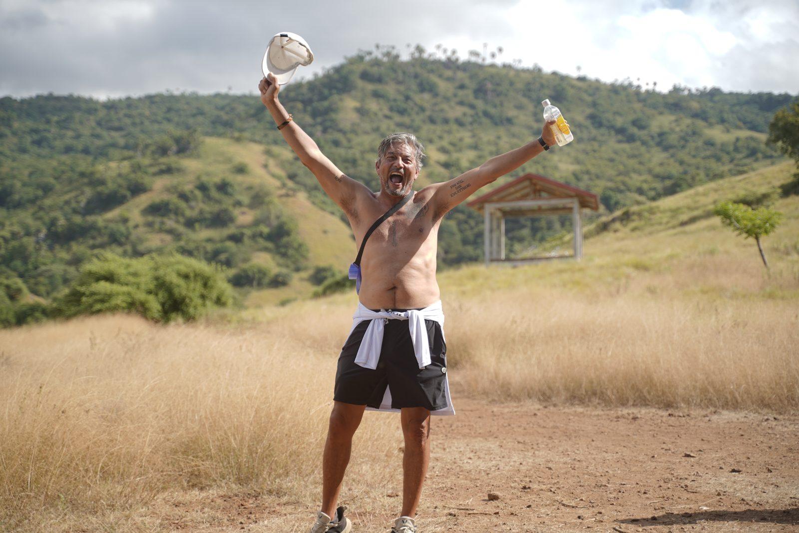 Komodo – Shirtless man cheering on savanna trail (Foto real de un viaje de Komodo Explorer)