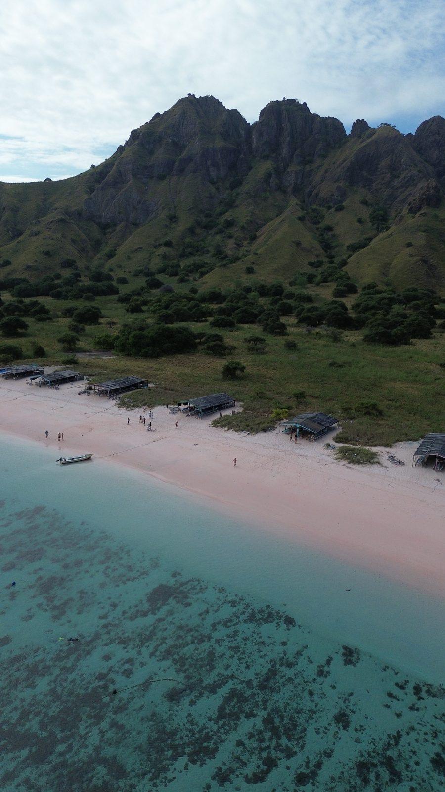 Pink Beach – Aerial pink beach below jagged green ridge (Echtes Foto von einer Komodo-Explorer-Fahrt)