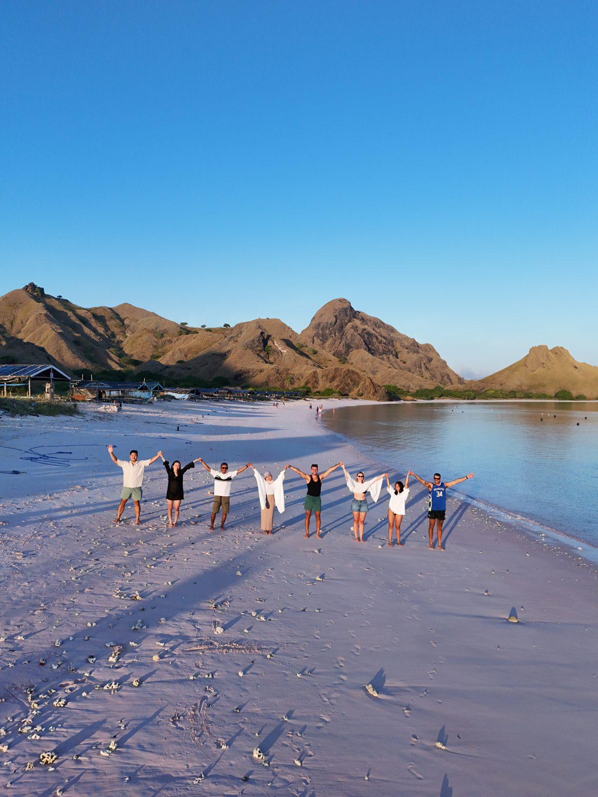 Pink Beach – Group in line on pink sand, hills behind (Echtes Foto von einer Komodo-Explorer-Fahrt)