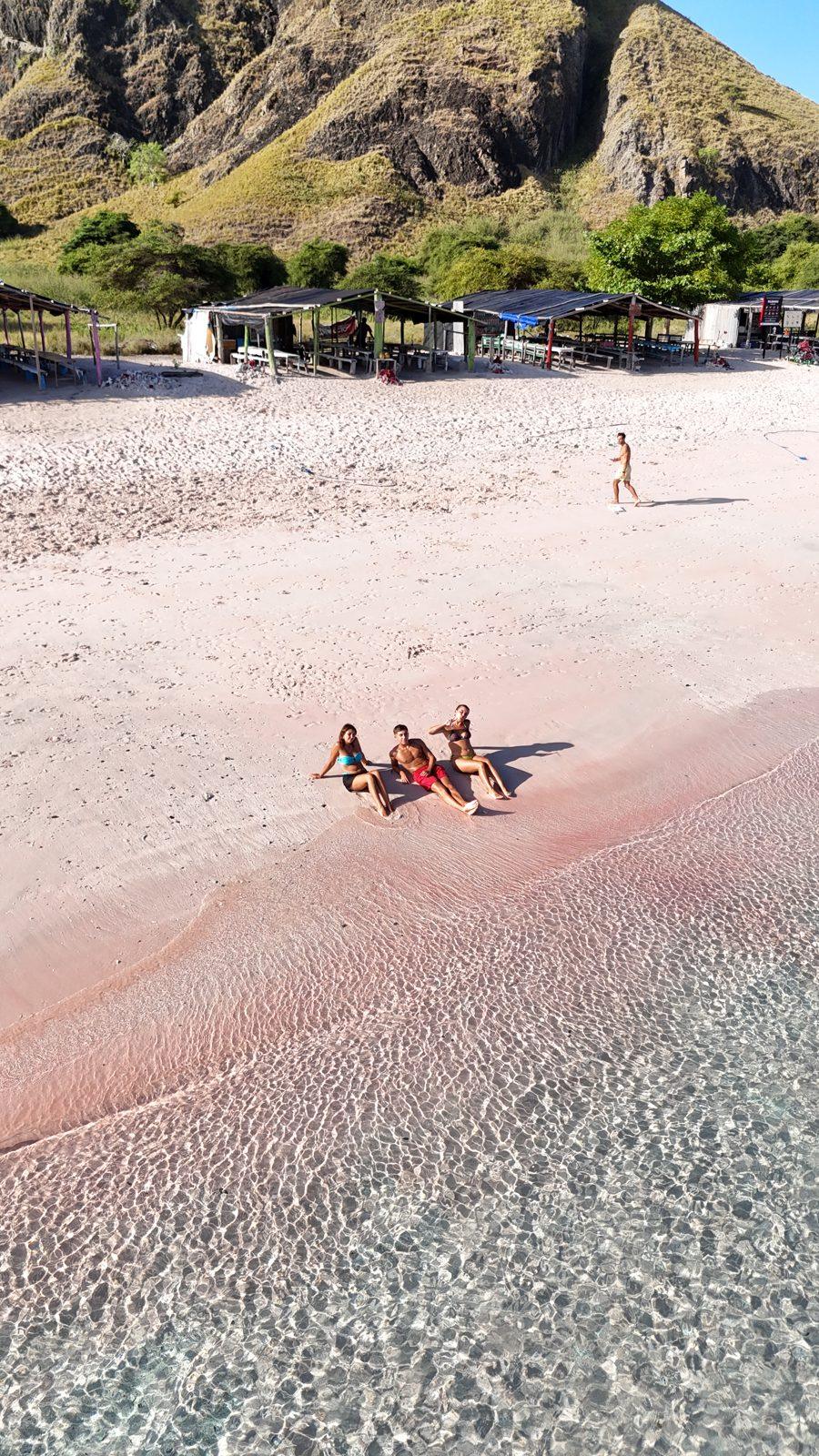 Pink Beach – group lying on pink sand, hill left (Echtes Foto von einer Komodo-Explorer-Fahrt)
