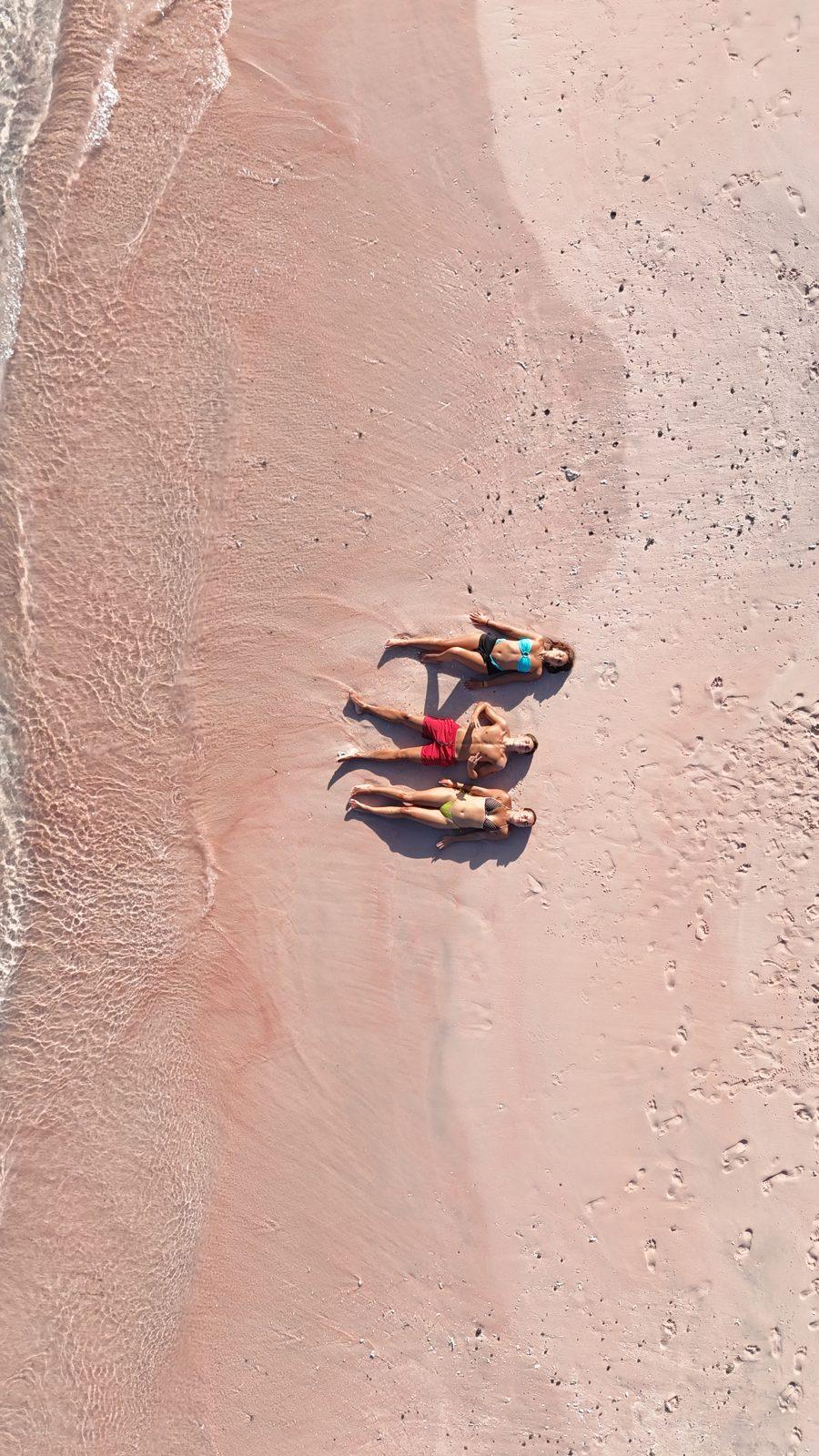 Pink Beach – two people lying on pink sand strip (Echtes Foto von einer Komodo-Explorer-Fahrt)